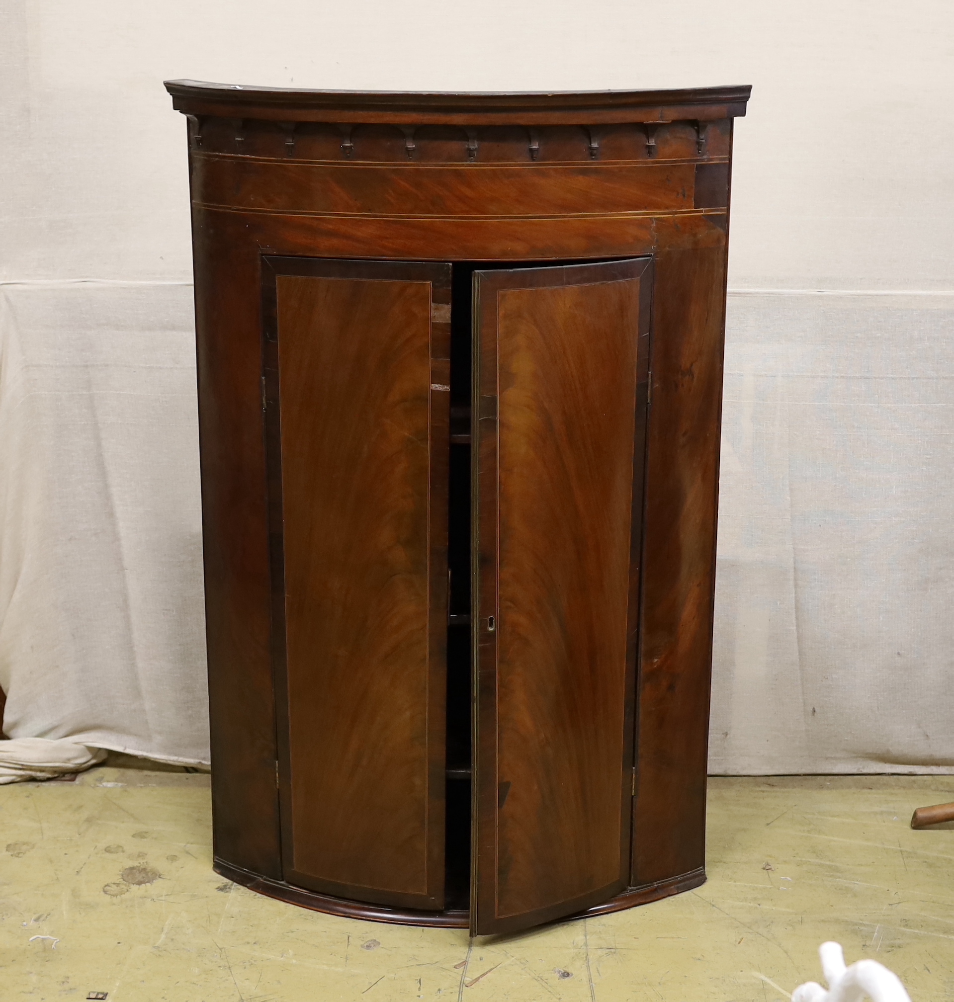 A 19th century George III bow-fronted hanging mahogany corner cupboard, width 84cm, depth 59cm, height 125cm